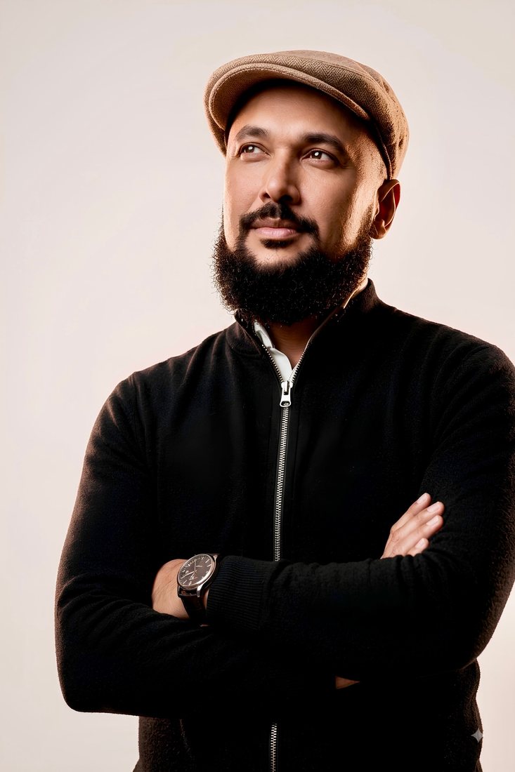 Khaalid Mooradd, arms crossed, in a flat cap and black jacket